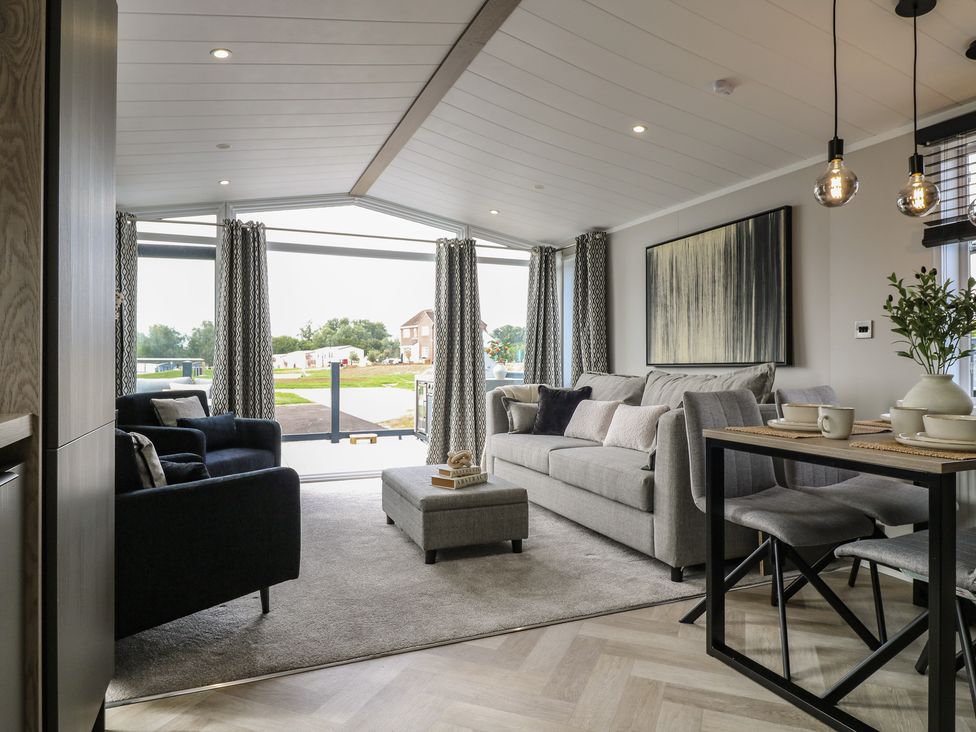 A living room with a sofa and dining area at Lodge 2 in St. Osyth