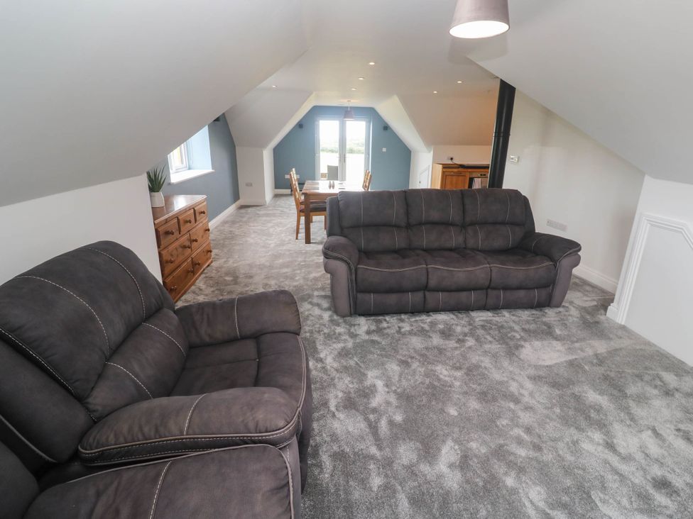 A living room with a sofa and a dining table at 6 Coswinsawsin Lane near Camborne
