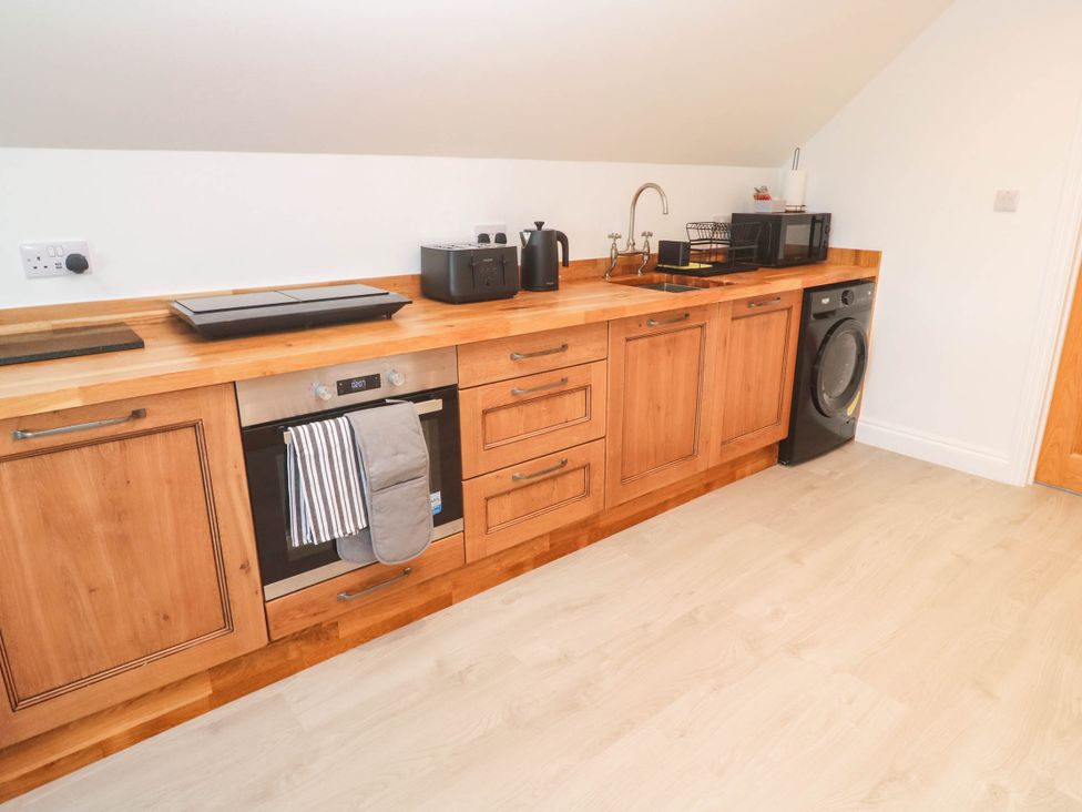 A kitchen with wooden cabinets and appliances at 6 Coswinsawsin Lane near Camborne