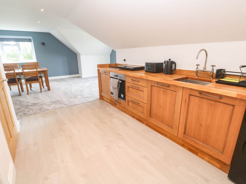 A kitchen with wooden cabinets and dining area at 6 Coswinsawsin Lane near Camborne