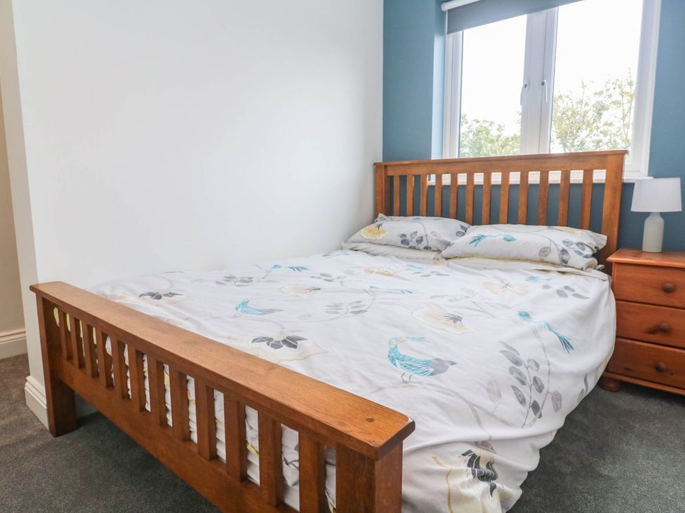 A bedroom with a wooden bed and bedside table at 6 Coswinsawsin Lane near Camborne