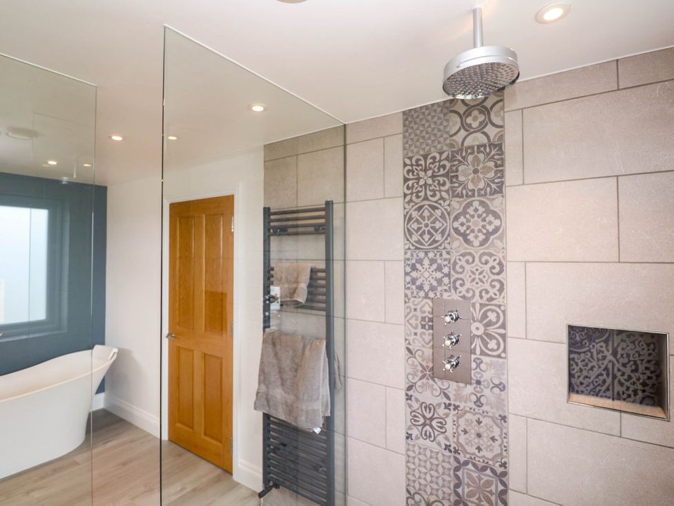 A bathroom with a bathtub and shower area at 6 Coswinsawsin Lane near Camborne