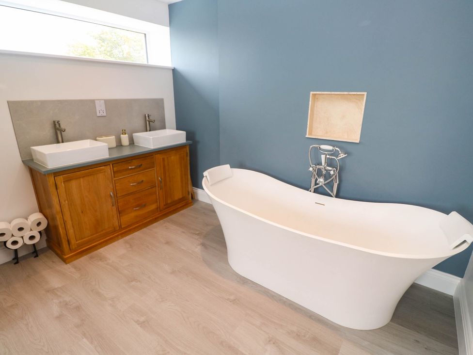 A bathroom with a bathtub and two sinks at 6 Coswinsawsin Lane near Camborne