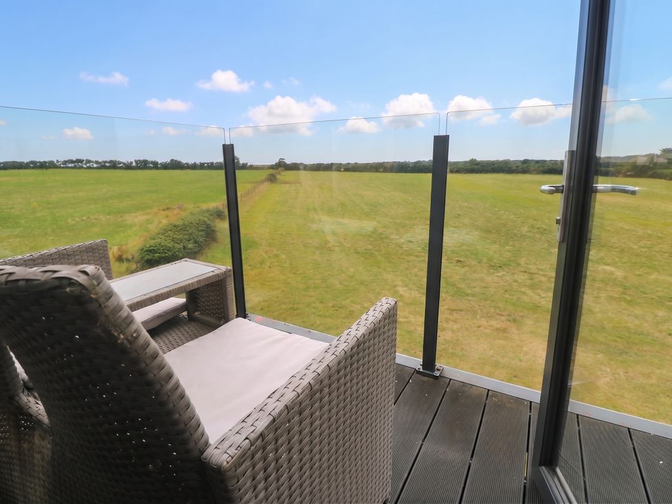 A balcony with chairs and table overlooking grassland at 6 Coswinsawsin Lane near Camborne