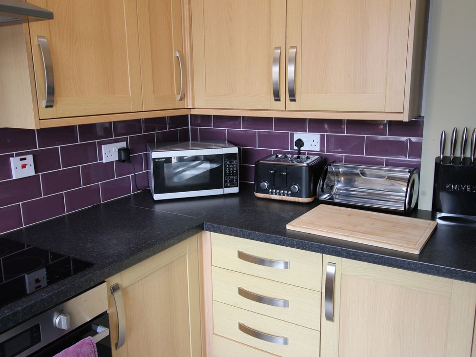A kitchen with a microwave, toaster, bread bin and cutting board at The Hampton in Scarborough