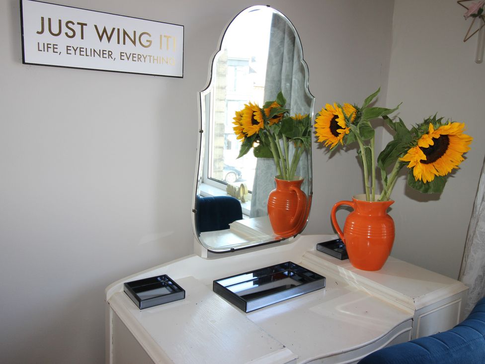 A dressing room with a mirror and sunflowers in a vase at The Hampton in Scarborough