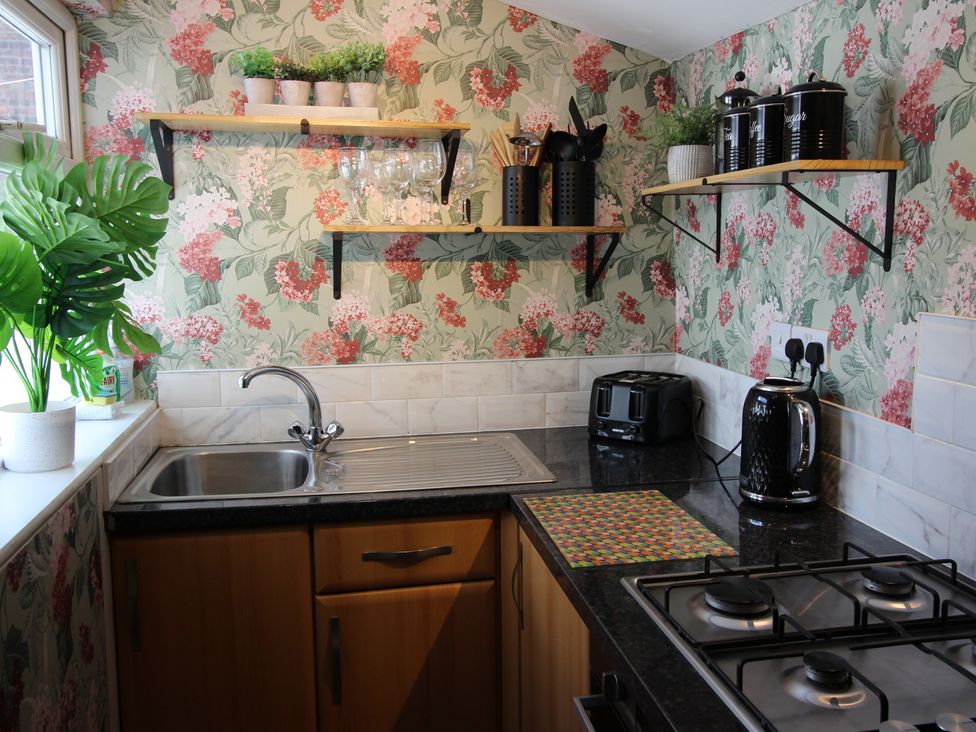 A kitchen with a sink, stove, and shelves at The Trafalgar in Scarborough