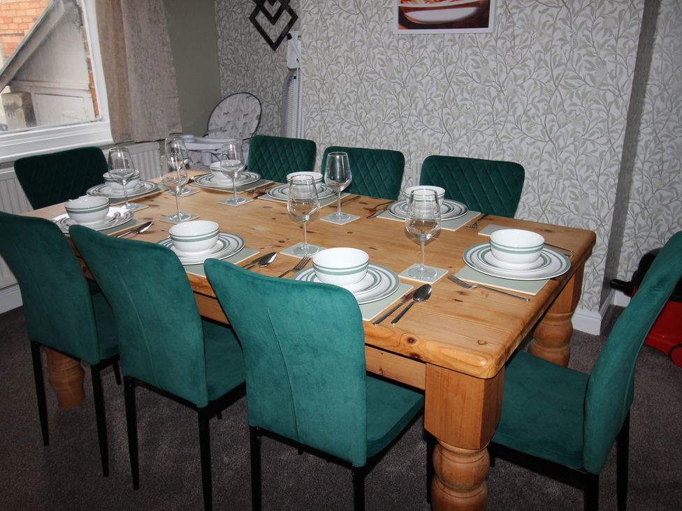 A dining room with a wooden table and green chairs at Brinkburn House in Scarborough
