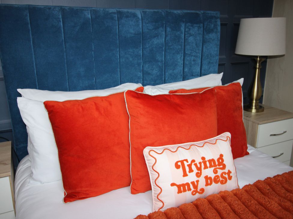 A bedroom with a blue headboard and orange pillows at Brinkburn House in Scarborough