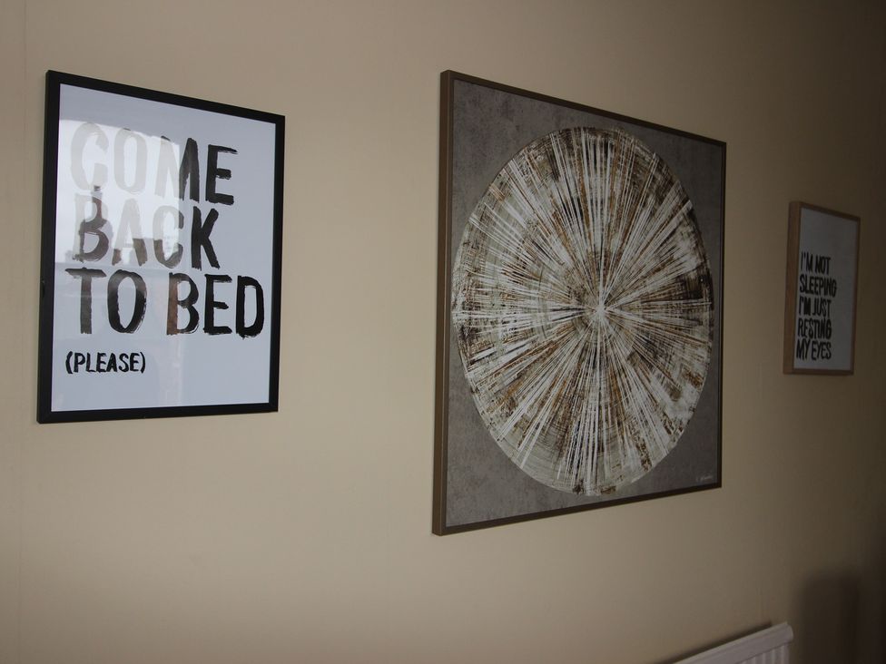 A wall with framed artwork and quotes in a living room at Brinkburn House in Scarborough
