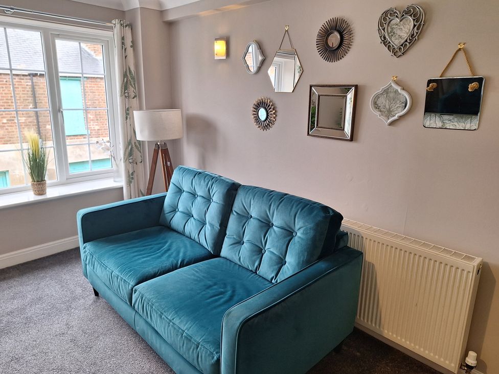 A living room with a sofa and decorative mirrors at Old Coach House Apartment in Scarborough
