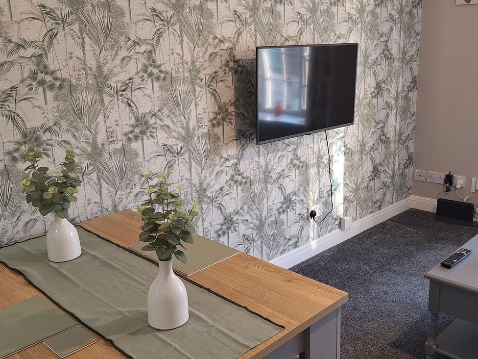 A living room with a TV, table and vases at Old Coach House Apartment in Scarborough