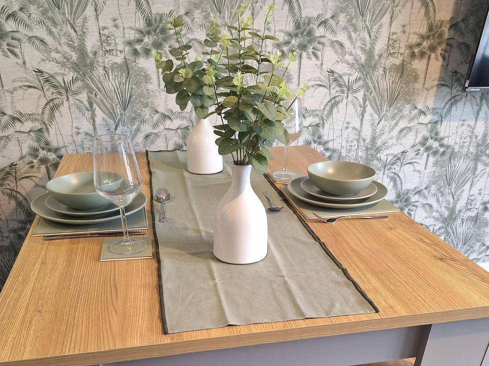 A dining table set with plates, glasses, and a vase at Old Coach House Apartment in Scarborough