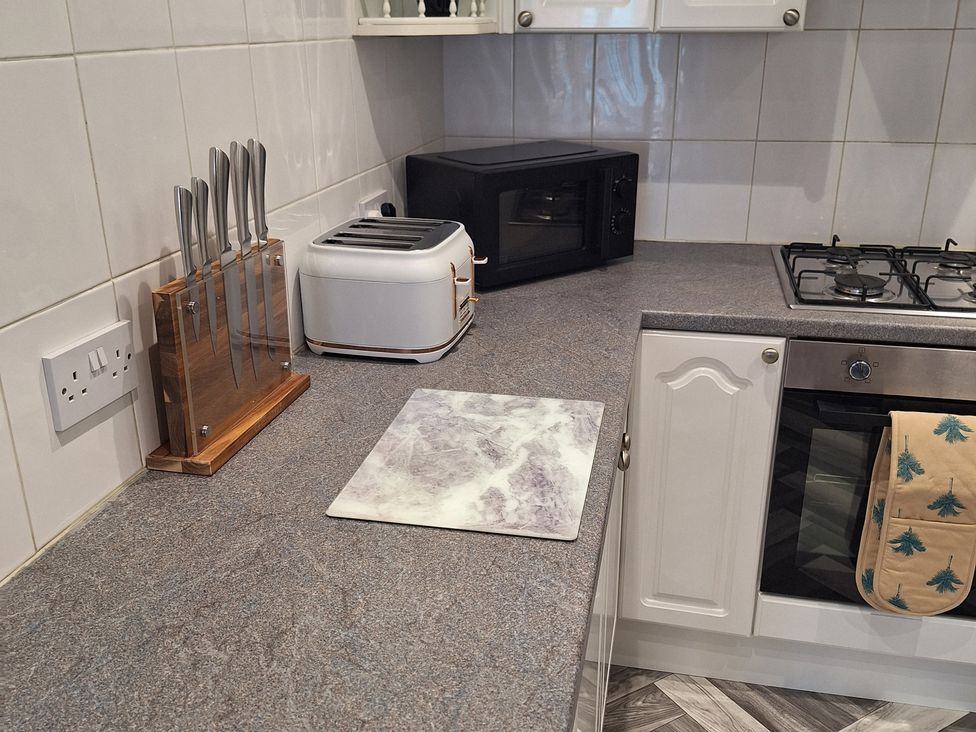 A kitchen with a counter, knives, toaster, microwave, and chopping board at Old Coach House Apartment in Scarborough