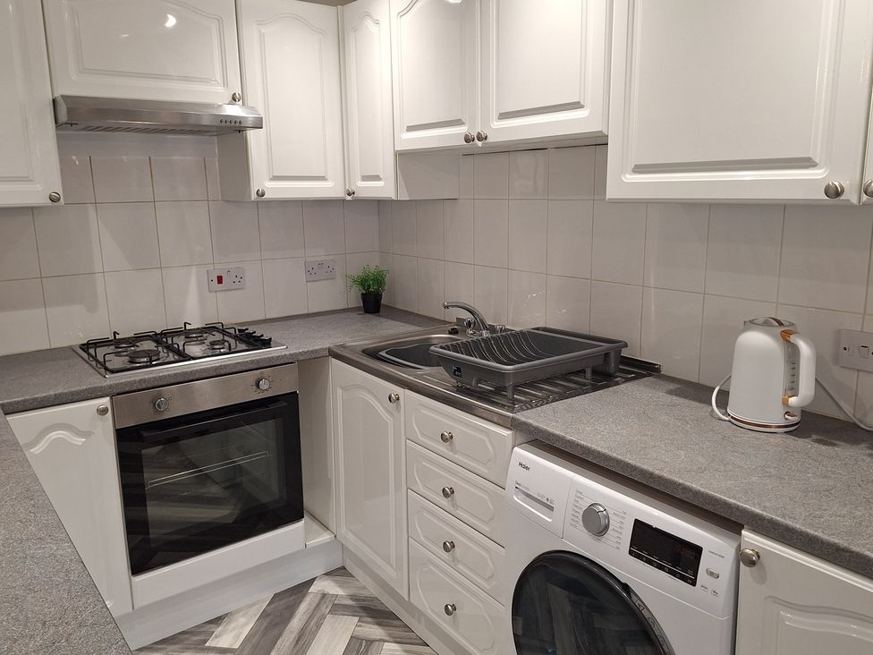 A kitchen with an oven, gas stove, sink, washing machine, and kettle at Old Coach House Apartment, Scarborough