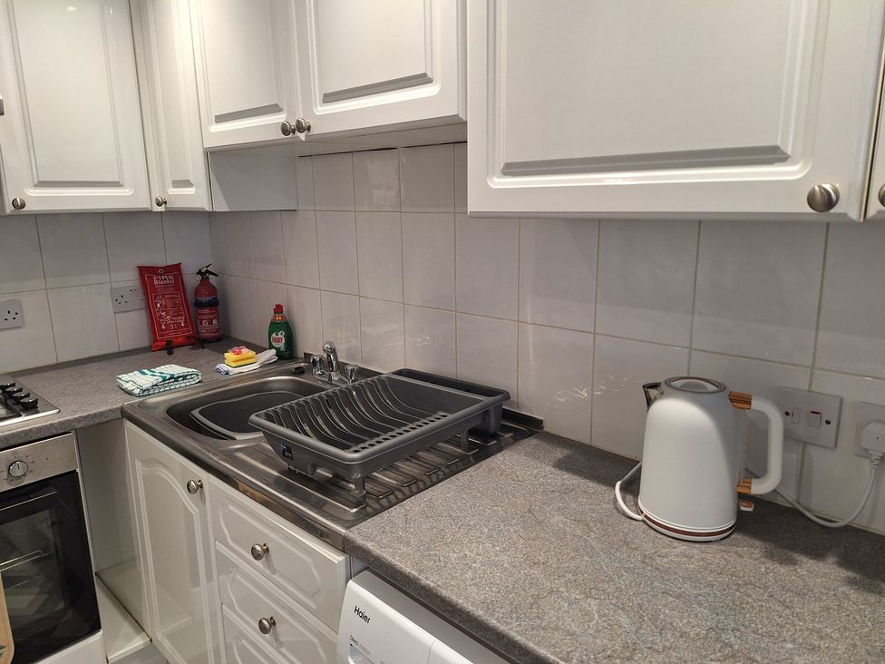 A kitchen with a sink and draining rack at Old Coach House Apartment in Scarborough