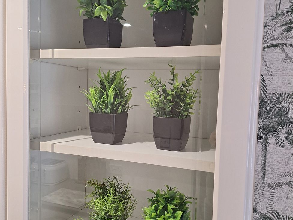 A display of artificial plants in pots on a shelf at Old Coach House Apartment in Scarborough