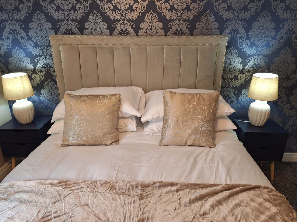 A bed with decorative pillows and lamps at Old Coach House Apartment in Scarborough