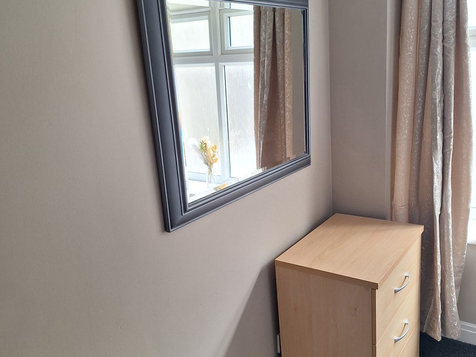 A bedroom with a mirror and a chest of drawers at Old Coach House Apartment in Scarborough