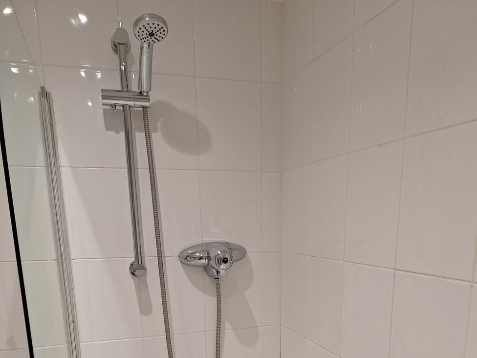 A shower with a handheld showerhead and control in the bathroom at Old Coach House Apartment Scarborough