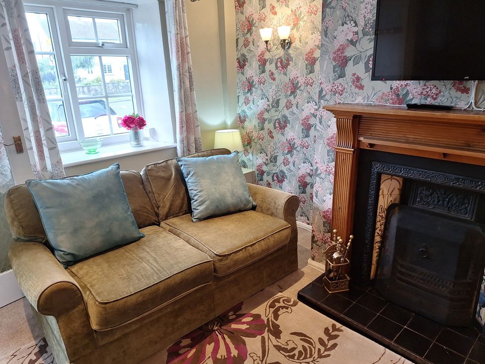 A living room with a sofa and a fireplace at Fryers Cottage in Seamer, North Yorkshire