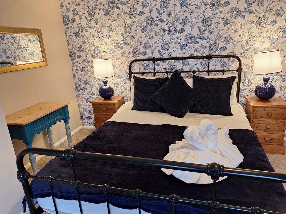 A bedroom with a bed, pillows, nightstand, and lamp at Fryers Cottage in Seamer, North Yorkshire