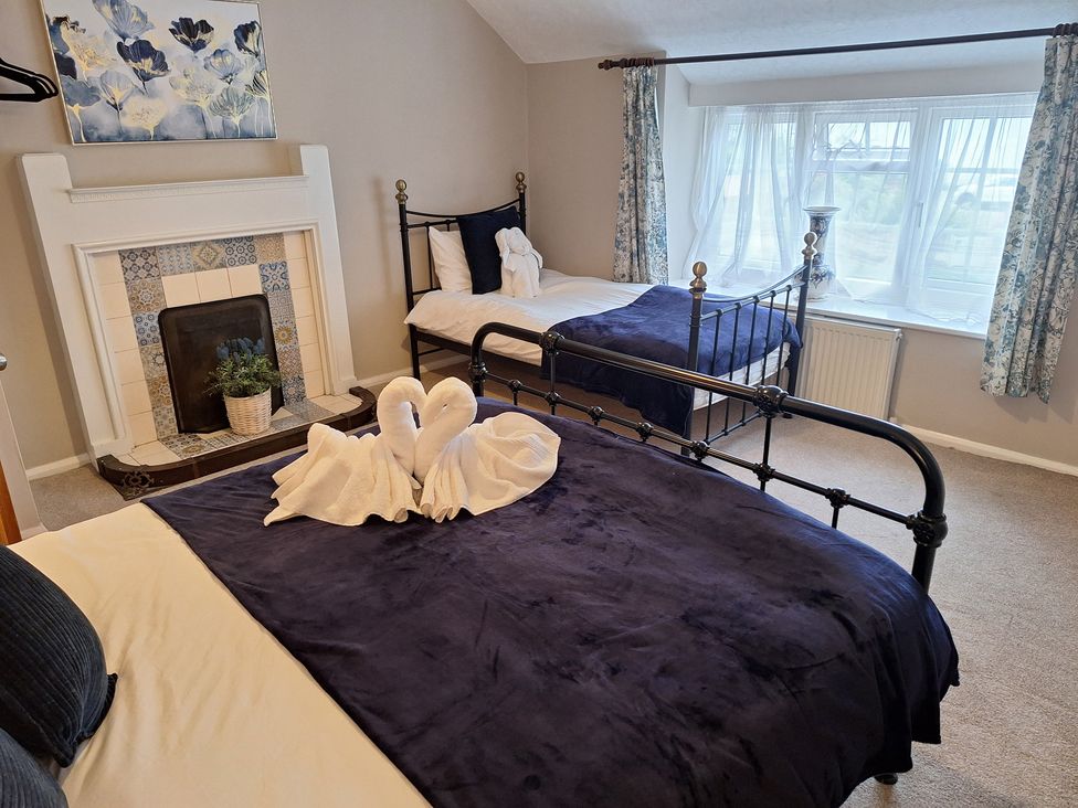 A bedroom with two beds and a fireplace at Fryers Cottage in Seamer, North Yorkshire