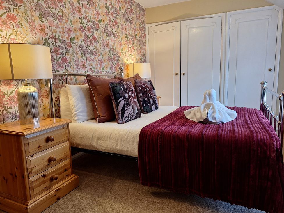 A bedroom with a bed, bedside table, and wardrobe at Fryers Cottage in Seamer, North Yorkshire