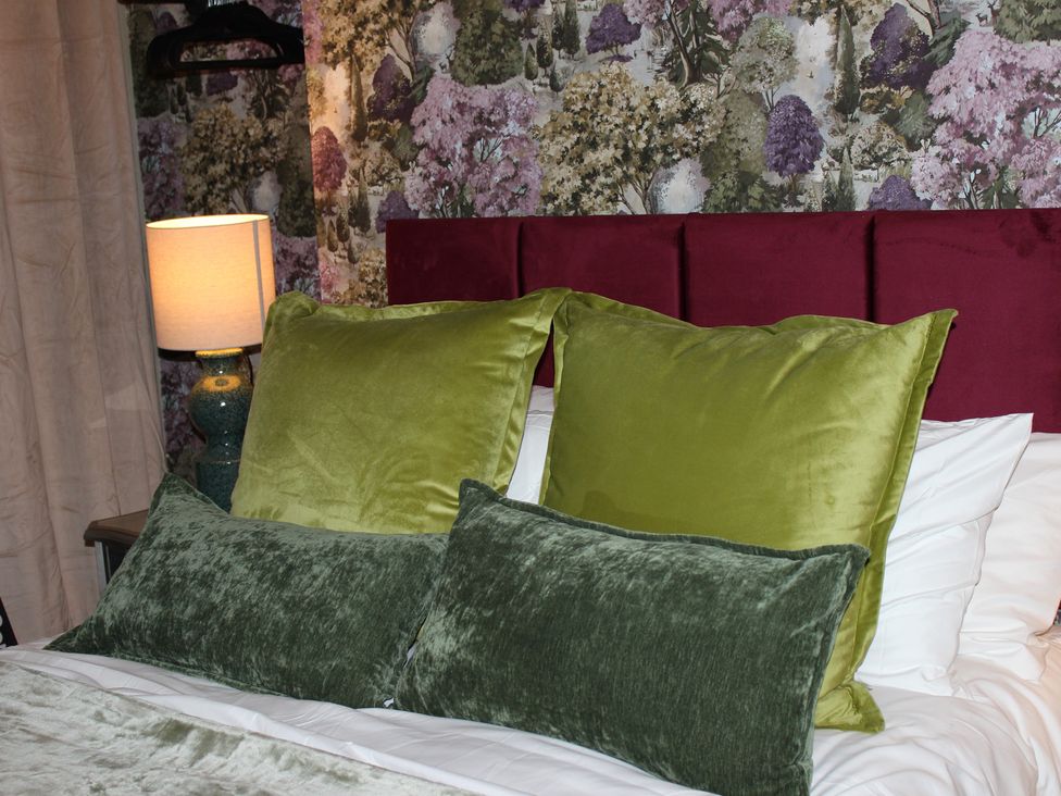 A bedroom with pillows on a bed and a lamp at Blackburn Heights Apartment 1, Bridlington