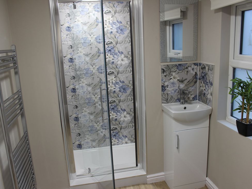 A bathroom with a shower, washbasin, and mirror at Blackburn Heights Apartment 1, Bridlington