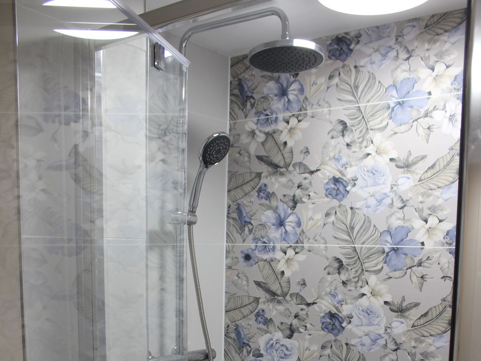 A shower with floral tiles at Blackburn Heights Apartment 1, Bridlington