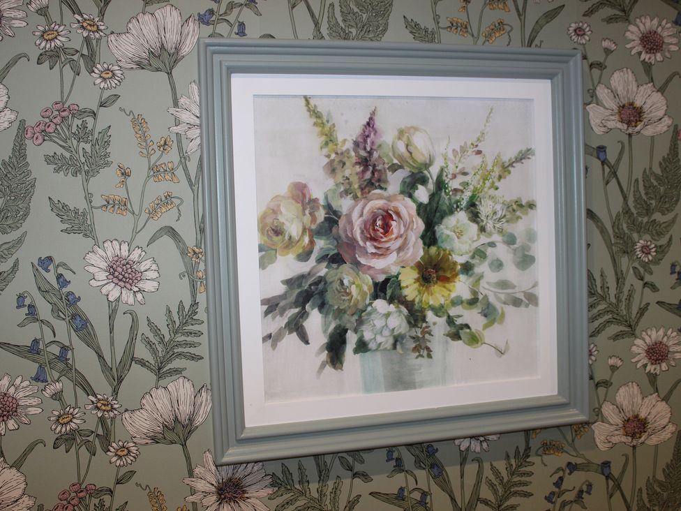 A floral painting framed on wallpaper at Blackburn Heights Apartment 1 in Bridlington