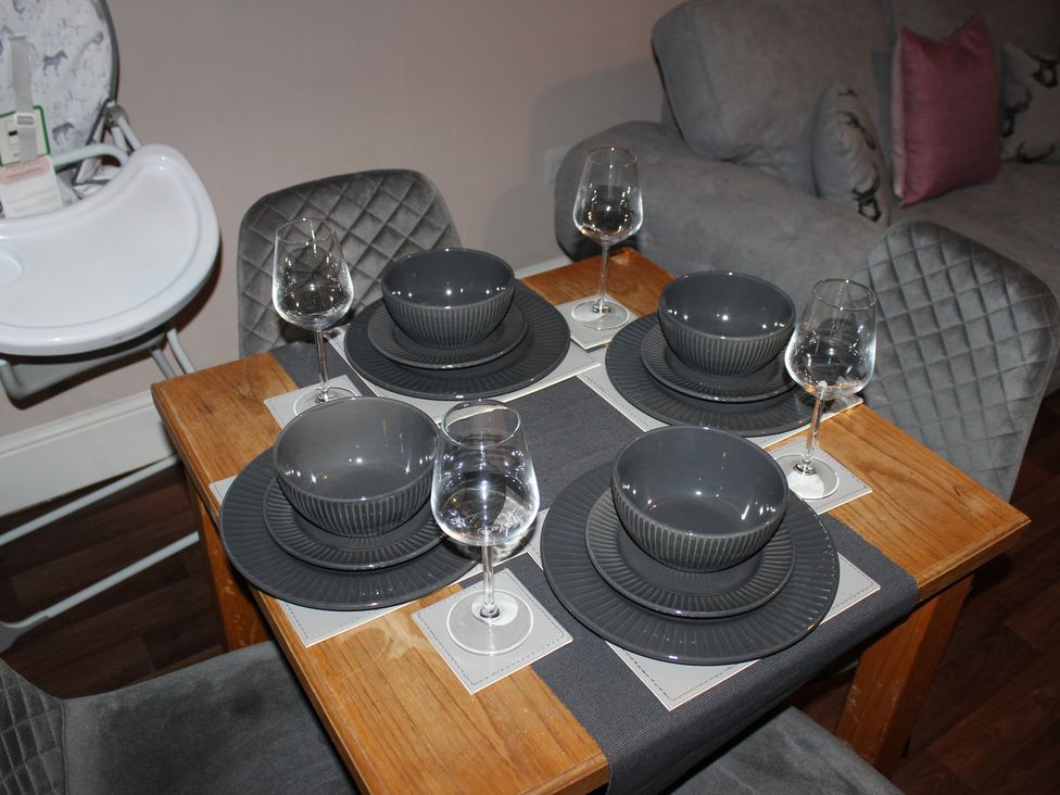 A dining table set with dinner plates and wine glasses at Blackburn Heights Apartment 3 in Bridlington