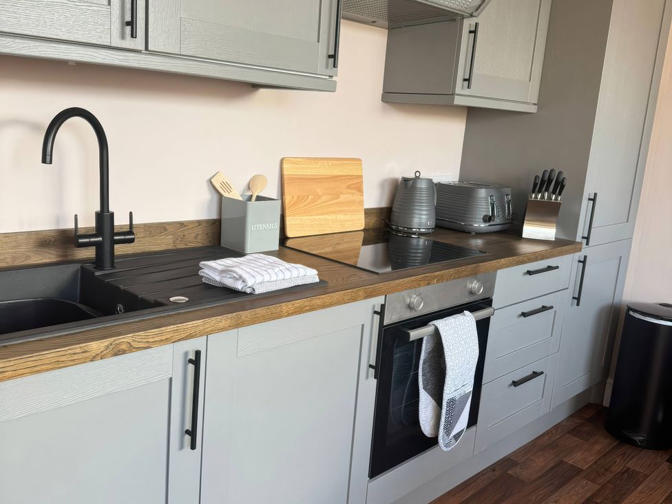 A kitchen with a sink, stove, and utensils at Blackburn Heights Apartment 3 in Bridlington