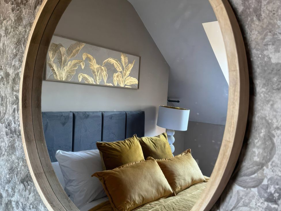A bedroom with a bed and lamp viewed through a round mirror at Blackburn Heights Apartment 3 in Bridlington