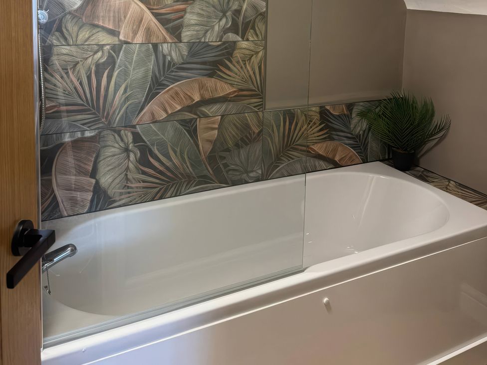 A bathroom featuring a bath tub and decorative wall tiles at Blackburn Heights Apartment 3, Bridlington