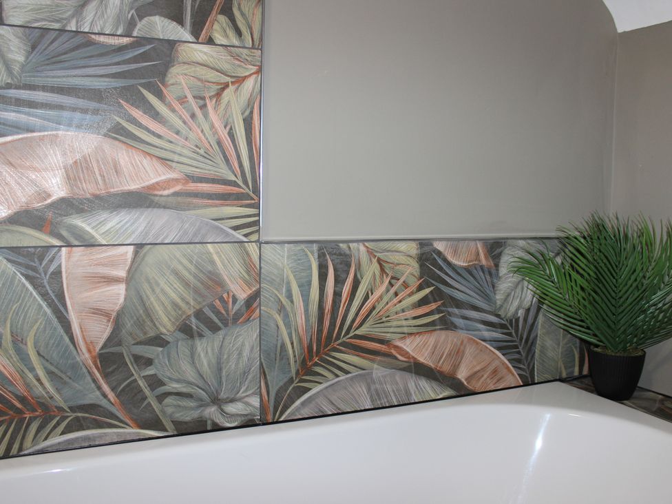A bathroom with patterned wall tiles and a potted plant at Blackburn Heights Apartment 3, Bridlington