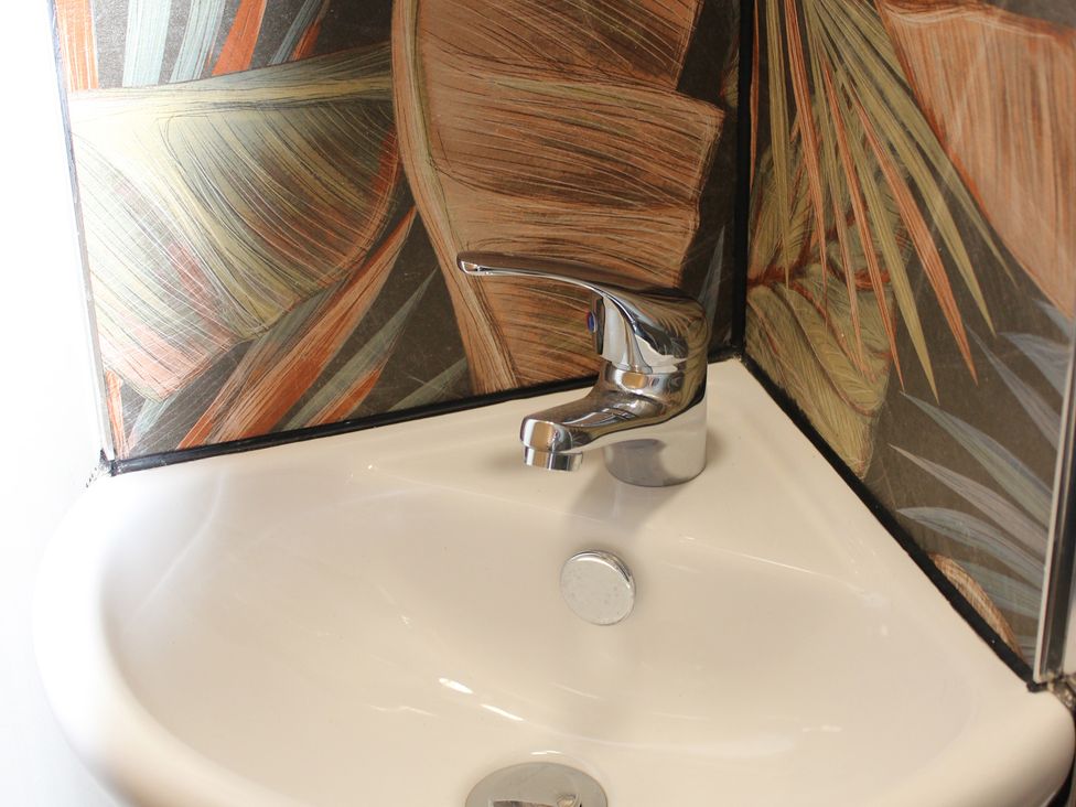 A sink with a faucet and wallpaper in a bathroom at Blackburn Heights Apartment 3, Bridlington