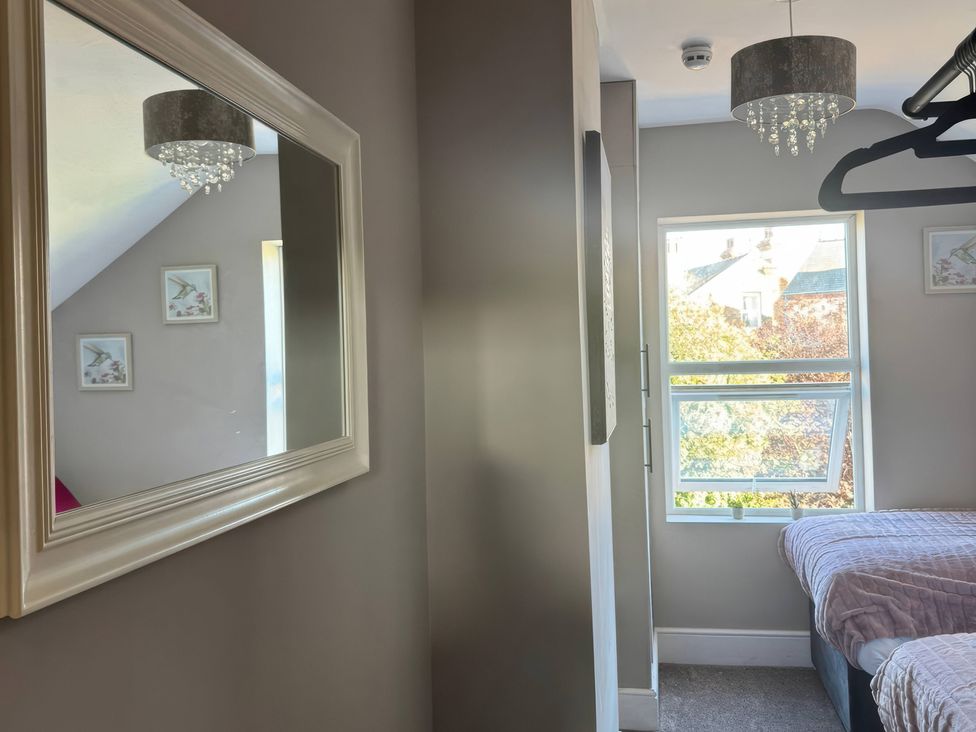 A bedroom with a mirror and a window at Blackburn Heights Apartment 3 in Bridlington