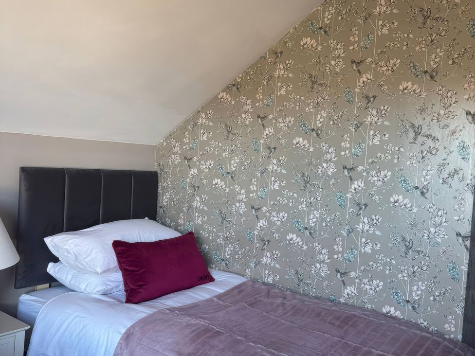 A bedroom with a single bed and floral wallpaper at Blackburn Heights Apartment 3 in Bridlington