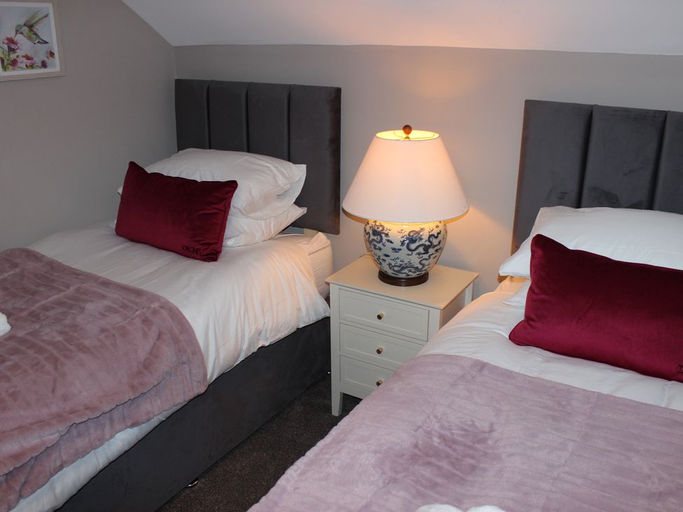 A bedroom with two beds and a bedside table with a lamp at Blackburn Heights Apartment 3 in Bridlington