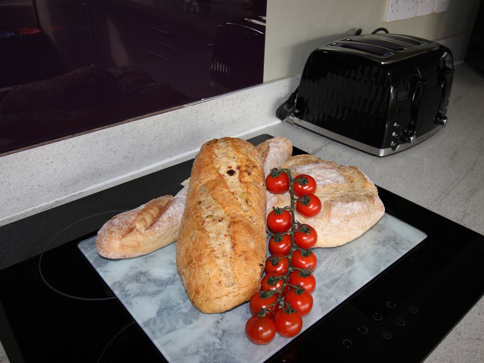 A kitchen countertop with bread and tomatoes at Cornerhouse Apartment 1, Llandudno