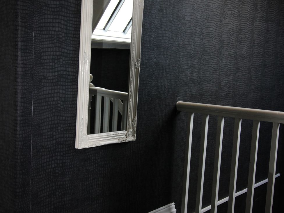A staircase with a mirror and handrail at Cornerhouse Apartment 1 in Llandudno
