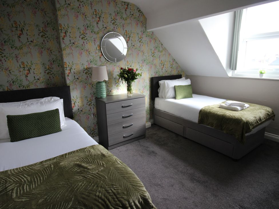 A bedroom with two beds and a nightstand at Cornerhouse Apartment 1 in Llandudno