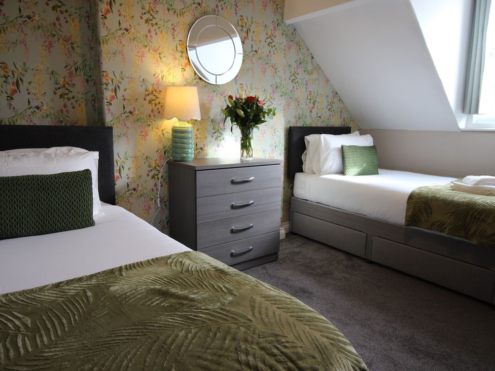 A bedroom with two beds and a nightstand at Cornerhouse Apartment 1 in Llandudno