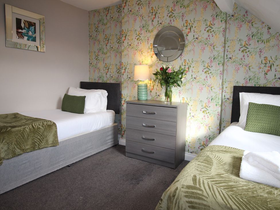 A bedroom with two beds and a dresser at Cornerhouse Apartment 1 in Llandudno