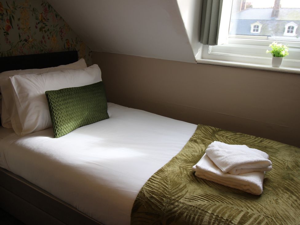 A bedroom with a bed and towels on it at Cornerhouse Apartment 1 in Llandudno