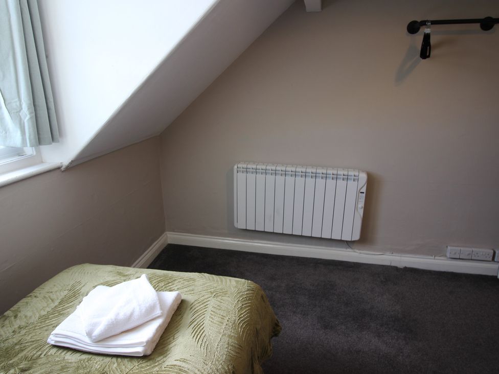 A bedroom with a bed and towels on it at Cornerhouse Apartment 1 in Llandudno