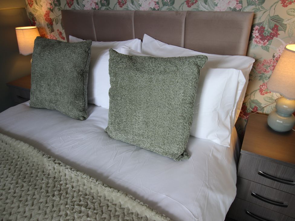 A bed with pillows and a bedside lamp at Cornerhouse Apartment 1 Llandudno