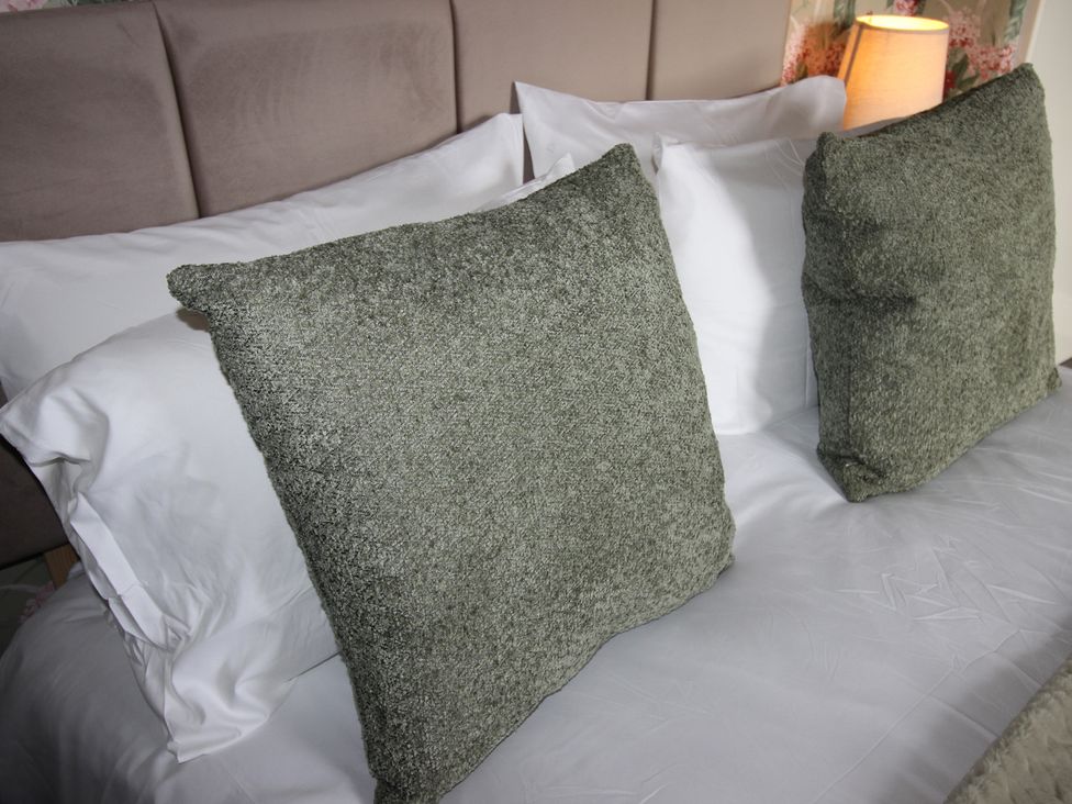 A bed with pillows and a lamp at Cornerhouse Apartment 1 Llandudno